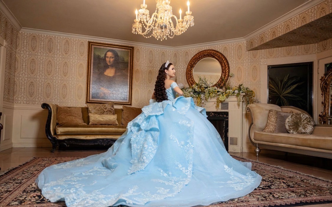 Carolina in the mansion parlor beneath a crystal chandelier