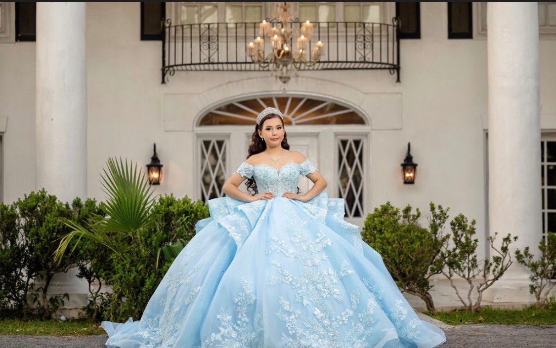 Carolina in front of the white mansion with a lit chandelier